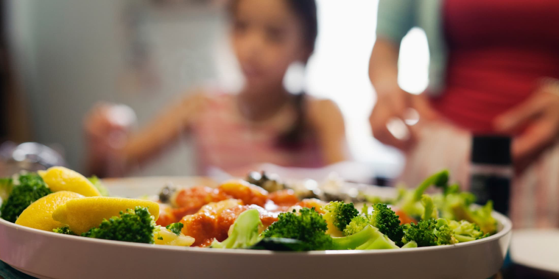 Colorful plate of pasta and broccoli at a family dinner table